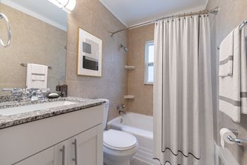Updated bathroom at Monon Court Apartments in Broad Ripple with granite vanity, modern fixtures, and tub-shower combo near Monon Trail.